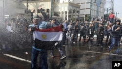 A protester holds an Egyptian flag as he stands in front of water canons during clashes in Cairo, Jan 28, 2011