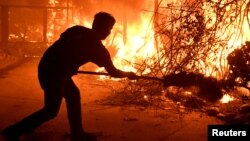 Home owner Will Buckley uses a shovel with dirt to try to stop the flames from from destroying a neighbor's home during the Woolsey Fire in Malibu, California, Nov. 9, 2018. 