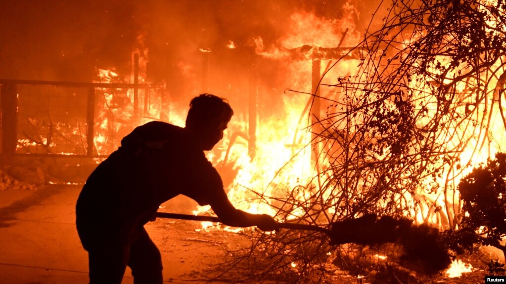 Home owner Will Buckley uses a shovel with dirt to try to stop the flames from from destroying a neighbor's home during the Woolsey Fire in Malibu, California, Nov. 9, 2018. 