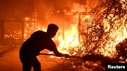 Home owner Will Buckley uses a shovel with dirt to try to stop the flames from from destroying a neighbor's home during the Woolsey Fire in Malibu, California, Nov. 9, 2018. 