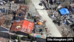 A house with the writings on the roof saying that food and water are needed is seen from a Philippine Air Force helicopter.