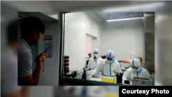 Cambodian medical personnel dressed in protective gear perform coronavirus testing in a lab. (Courtesy of Cambodia's Communicable Disease Control Department)