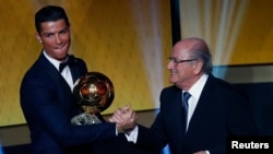 Pemain depan Real Madrid dan Portugal Cristiano Ronaldo menerima piala FIFA Ballon d'Or dari Presiden FIFA Joseph Blatter dalam upacara di Zurich (12/1). (Reuters/Ruben Sprich)