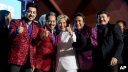 Democratic presidential candidate Hillary Clinton, center, pose with members of the band Los Tigres del Norte at a debate watch party at the Craig Ranch Regional Amphitheater in North Las Vegas, Oct. 19, 2016.