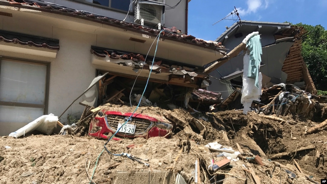 A car is covered with mud as houses are damaged after a mudslide caused by heavy rains in Hiroshima, southwestern Japan, July 10, 2018.