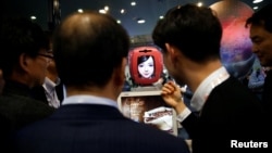 FILE - Attendees interact with Commerce Bot, a robot that provides customer service with artificial intelligence technology and voice recognition, at SK telecom's stand at the Mobile World Congress in Barcelona, Spain, Feb. 28, 2017. 
