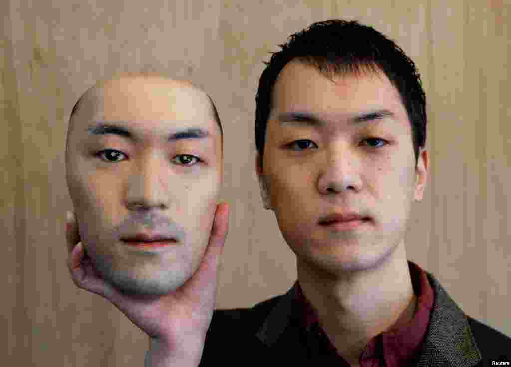 Shuhei Okawara, owner of the mask store Kamenya Omote in Tokyo, Japan, holds a super-realistic face mask of his real face, made by using 3D printing technology.
