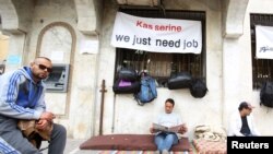 Mohamed Zied el Harizi (tengah), 37, pengangguran dari kota Kasserine, membaca koran di tengah protes dekat Kementerian Pelatihan Kejuruan dan Tenaga Kerja, menuntut lapangan pekerjaan, di Tunis, Tunisia (1/4).