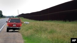 A mail carrier makes a delivery along a section of border fence in Brownsville, Texas, Nov. 14, 2016.