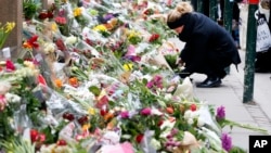 People place flower tributes at the synagogue in Copenhagen, Denmark, Feb. 16, 2015.