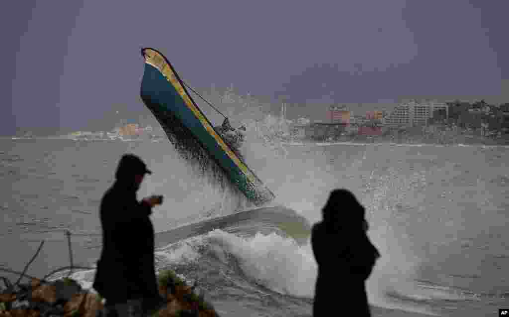 Palestinian fishermen ride their boat on windy and rainy day at the sea in Gaza City.