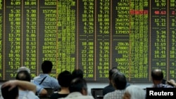 Para investor melihat informasi saham di sebuah papan elektronik di tempat pialang saham di Hangzhou, provinsi Zhejiang, China (25/8). 