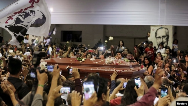 La gente reacciona cuando el ataúd que sostiene el cuerpo del ex presidente de Perú, Alan García, llega a la sede del partido APRA.