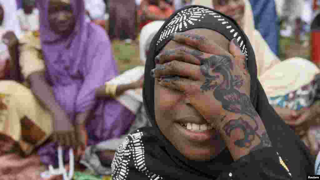 A girl covers her face as she waits for the start of prayers.