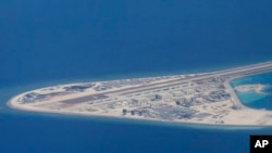 菲律賓空軍一架運輸機在南中國海中國造的人造島礁渚碧礁上空飛越時拍攝的照片，顯示人造島礁上的簡易機場和建築物。 （2017年4月21日）