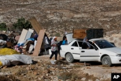 In this Tuesday, August 16, 2016 photo, Palestinians pack their belongings after their family house was demolished by Israeli troops in the West Bank village of Sair, near the town of Hebron. Israel said houses were destroyed because lack of building permit, while Palestinians say permits are virtually impossible to obtain and that Israel is evicting them from their land.