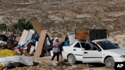 Warga Palestina mengepak barang-barang mereka setelah rumah mereka dihancurkan oleh pasukan Israel di desa Sair, Tepi Barat, dengan alasan tidak ada izin bangunan (16/8). (AP/Nasser Shiyoukhi)