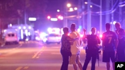 Orlando Police officers direct family members away from a multiple shooting at a nightclub in Orlando, Fla., Sunday, June 12, 2016. A gunman opened fire at a nightclub in central Florida, and multiple people have been wounded, police said Sunday.