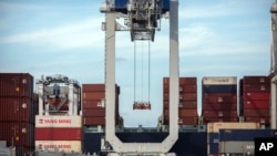FILE - A ship-to-shore crane prepares to load a 40-foot shipping container onto a container ship at the Port of Savannah in Savannah, Georgia, July 5, 2018.