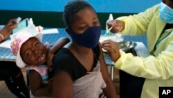 FILE - A mother receives her Pfizer vaccine against COVID-19 in Diepsloot Township near Johannesburg, Oct. 21, 2021. A new COVID-19 variant has been detected in South Africa that scientists say has a high number of mutations, Minister of Health Joe Phaahl