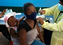 جوہانسبرگ میں ایک خاتون اپنے بچے کو ویکسین لگوا رہی ہے۔ افریقہ میں ویکسین لگانے کی شرح صرف 7 فی صد ہے۔