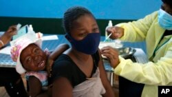 FILE - A mother receives her Pfizer vaccine against COVID-19 in Diepsloot Township near Johannesburg, Oct. 21, 2021. 