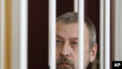 Former presidential candidate Andrei Sannikov sits in a cage during a court hearing in Minsk, April 27, 2011