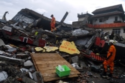 Tim SAR memeriksa bangunan yang roboh akibat guncangan gempa di Mamuju, Sulawesi Barat, Sabtu, 16 Januari 2021. (Foto: Antara Foto/Sigid Kurniawan via Reuters)