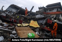Tim SAR memeriksa bangunan yang roboh akibat guncangan gempa di Mamuju, Sulawesi Barat, Sabtu, 16 Januari 2021. (Foto: Antara Foto/Sigid Kurniawan via Reuters)