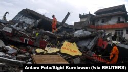 Para petugas SAR memeriksa bangunan yang roboh akibat guncangan gempa di Mamuju, Sulawesi Barat, Sabtu, 16 Januari 2021. (Foto: Antara Foto/Sigid Kurniawan via Reuters)