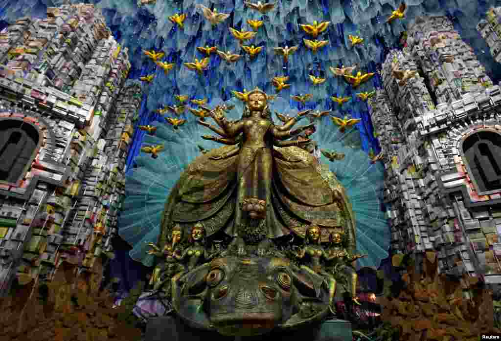 អ្នក​ធ្វើ​ការ​ខាង​អគ្គិសនី​ម្នាក់​ព្យួរ​ភ្លើង​ពណ៌​នៅ​លើ​រូប​សំណាក​ព្រះ Durga សម្រាប់​ពិធីបុណ្យ Durga Puja ដែល​នឹង​ជិត​ចូល​មក​ដល់ ក្នុង​ក្រុង Kolkata ប្រទេស​ឥណ្ឌា។