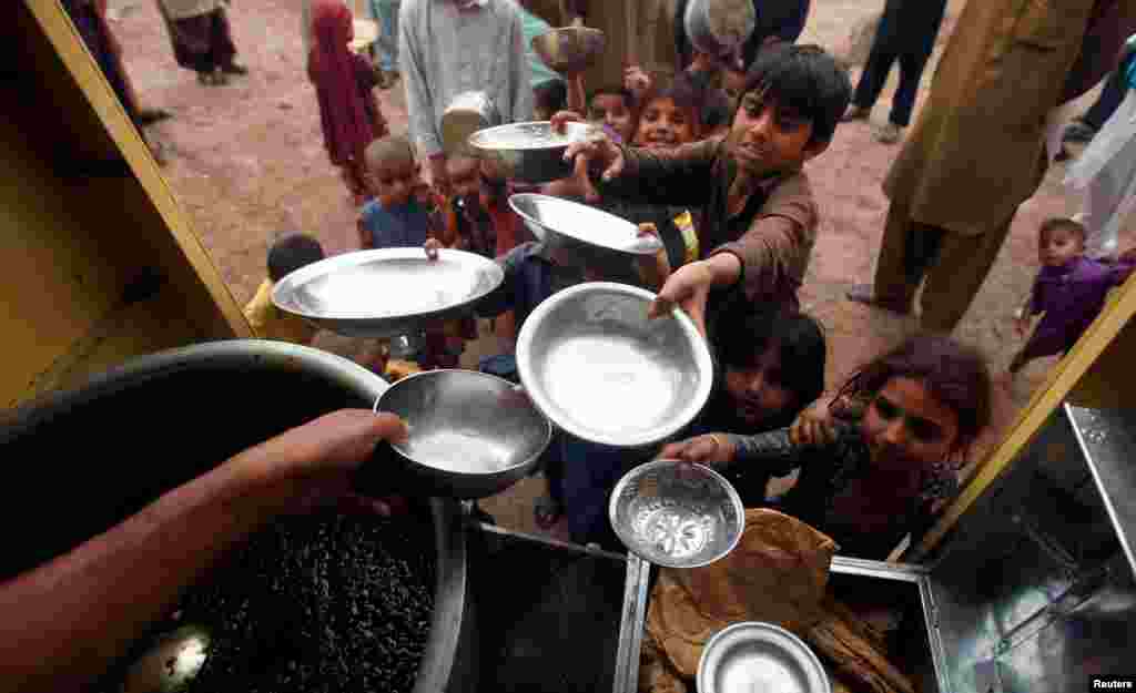 Anak-anak fakir miskin antri untuk menerima pembagian makanan di Peshawar, Pakistan.