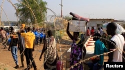 Displaced people walk past razor wire at Tomping camp, where some 15,000 displaced people who fled their homes are sheltered by the United Nations, near Juba, South Sudan, Jan. 7, 2014.