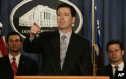 FILE - Deputy Attorney General James B. Comey, center, gestures during a news conference at the Department of Justice in Washington, April 12, 2005. Behind Comey are prosecutor George Z. Toscas, left, and Assistant Attorney General Christopher Wray.