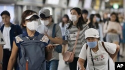 FILE - Passengers wearing masks as a precaution against the MERS virus make their way after they got off a train at a subway station in Seoul, South Korea, June 18, 2015.