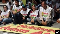 Kurds sit next to a banner that reads 'government, take steps' after Kurdish rebels gave Turkey a 'final warning' to take steps that would move forward peace talks aimed at ending a 30-year old conflict that has claimed tens of thousands of lives, in Anka