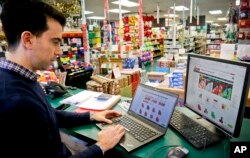 FILE - Andrew Jacobs, owner of JAM Paper and Envelope, goes online to his company's e-commerce site, in New York, Dec. 15, 2016. JAM got so much of its revenue online that it scaled back from five stores to one.