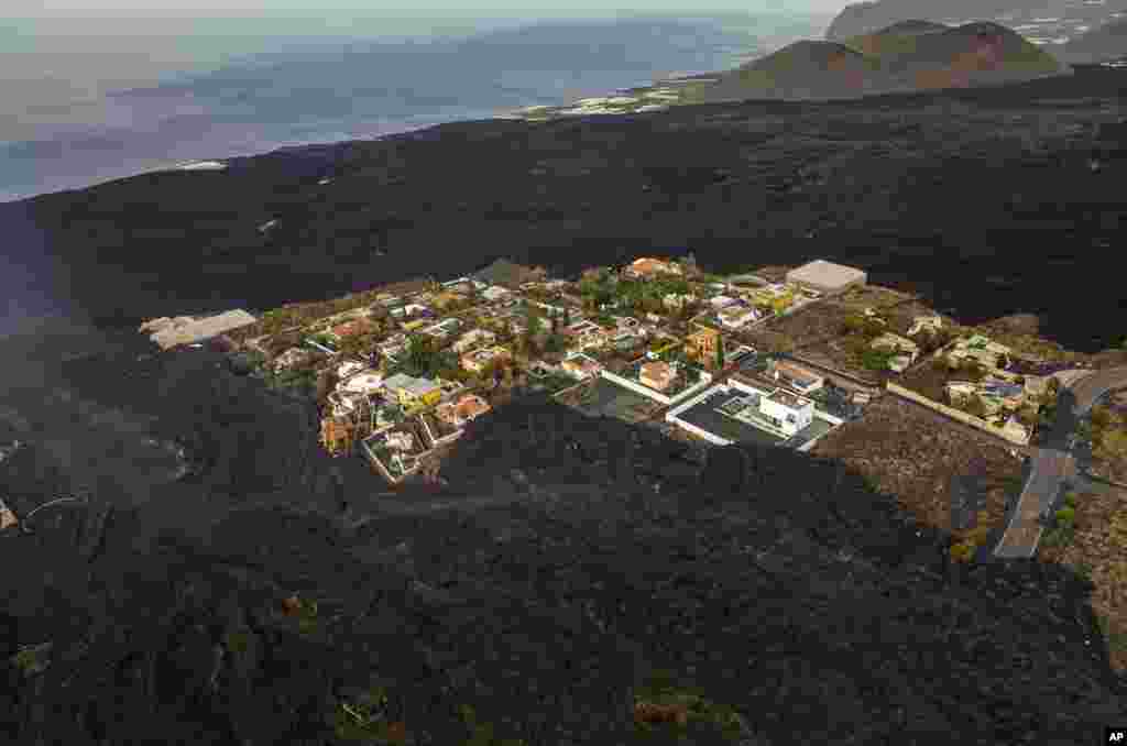 Houses remain isolated as lava from a volcano flows on the Canary island of La Palma, Spain.