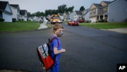 Paul Adamus, 7, waits at the bus stop for the first day of school on Monday, Aug. 3, 2020, in Dallas, Ga. (AP Photo/Brynn Anderson)
