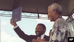 Chairman of the Constitutional Assembly, Cyril Ramaphosa, left, holds up a copy of the country's new constitution, was signed by President Nelson Mandela, right, in Sharpville, December 10, 1996. (file photo)