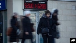People walk past electronic display board with figures indicating US dollar to Russian ruble currency exchange rate, St. Petersburg, Russia, Dec. 29, 2014.