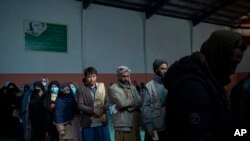 People wait in a line to receive cash at a money distribution organized by the World Food Program in Kabul, Afghanistan, Nov. 3, 2021.