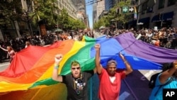 Mark Wilson, right, helps carry a rainbow flag during San Francisco's 42nd annual Gay Pride parade on Sunday, June 24, 2012. (AP Photo/Noah Berger)
