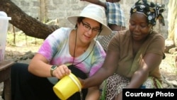 Sara Laskowski, left, gets a cooking lesson from her Peace Corps ‘host mother’ in Dubreka, Guinea. Pulled from the country because of Ebola fears, Laskowski promotes an Ebola relief fund for the region. (Photo courtesy of Sara Laskowski) 