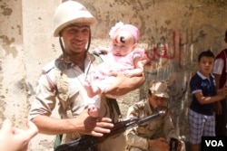 An Egyptian soldier poses with a baby with the letters "CC" on her forehead standing for president Sissi in front of one of the polling stations in Bashteel in Giza, Egypt. Sissi has enjoyed support from Egypt's army, long regarded as a pillar of stability in the country, May 26, 2014. (H. Elrasam/VOA)