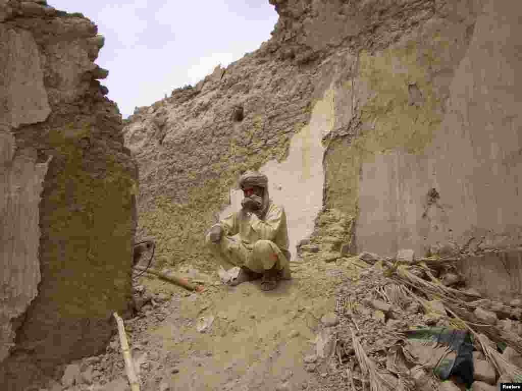 A earthquake survivor sits on the rubble of his mud house after it collapsed following the quake in the town of Mashkeel, southwestern Pakistani province of Baluchistan, near the Iranian border.