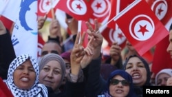 People wave national flags during demonstrations on the seventh anniversary of the toppling of president Zine El-Abidine Ben Ali, in Tunis, Jan. 14, 2018.