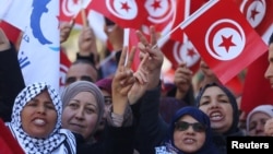 People wave national flags during demonstrations on the seventh anniversary of the toppling of president Zine El-Abidine Ben Ali, in Tunis, Jan. 14, 2018.