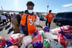 Denver Broncos cornerback Essang Bassey selects frozen turkeys to place in Thanksgiving Day banquet boxes in a vehicle, Nov. 23, 2021, outside Empower Field at Mile High in Denver, Colorado.