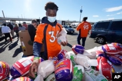 Denver Broncos cornerback Essang Bassey selects frozen turkeys to place in Thanksgiving Day banquet boxes in a vehicle, Nov. 23, 2021, outside Empower Field at Mile High in Denver, Colorado.